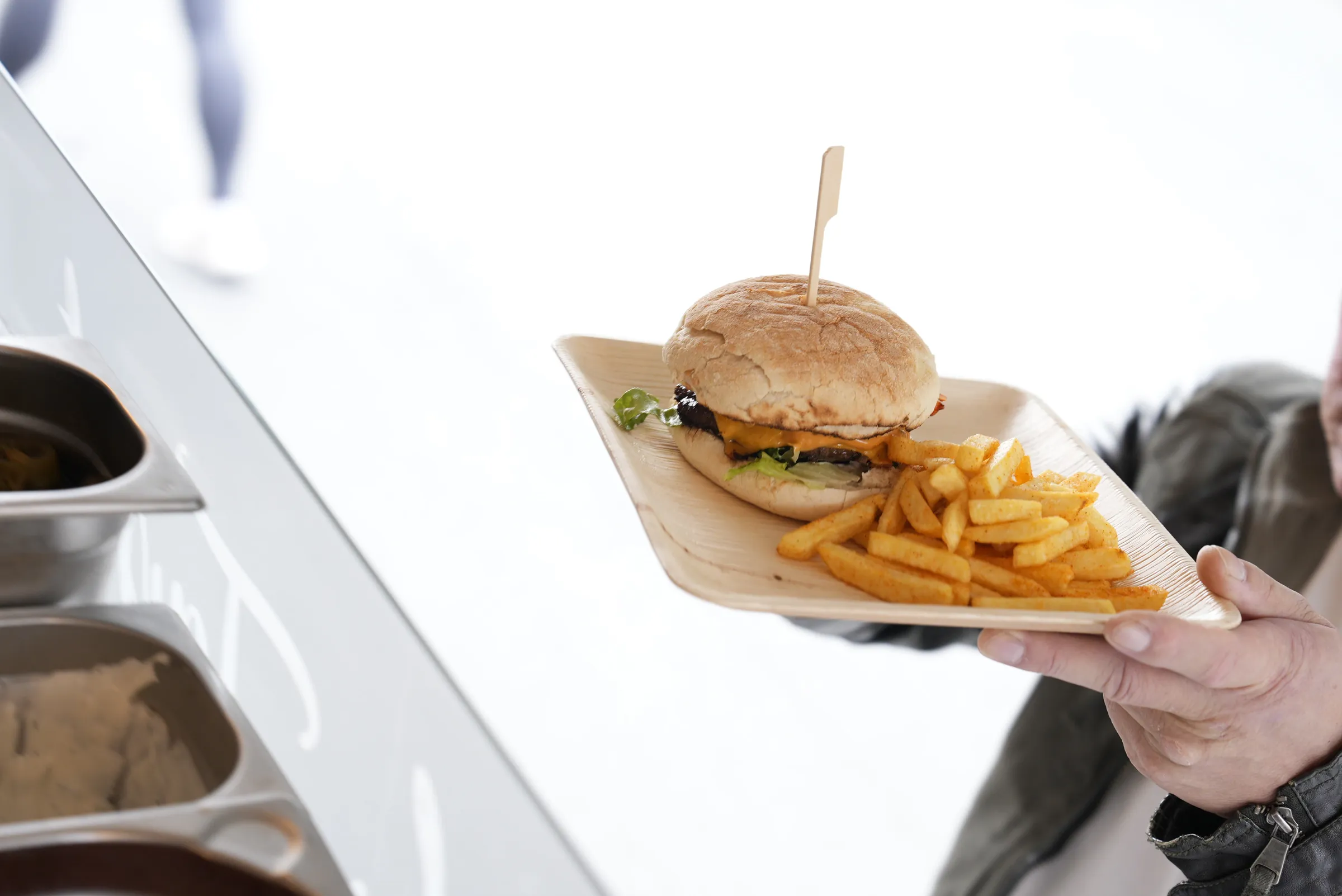 Burger mit Pommes wird an der Theke des La Tapita Foodtrucks ausgegeben