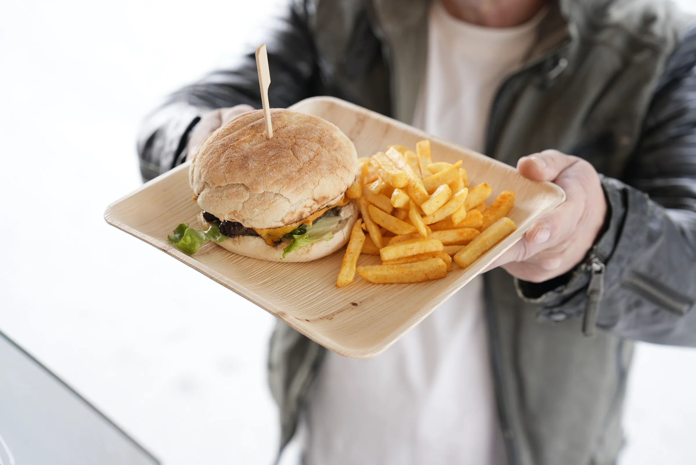 Gast hält Burger mit Pommes von La Tapita bei einem Event