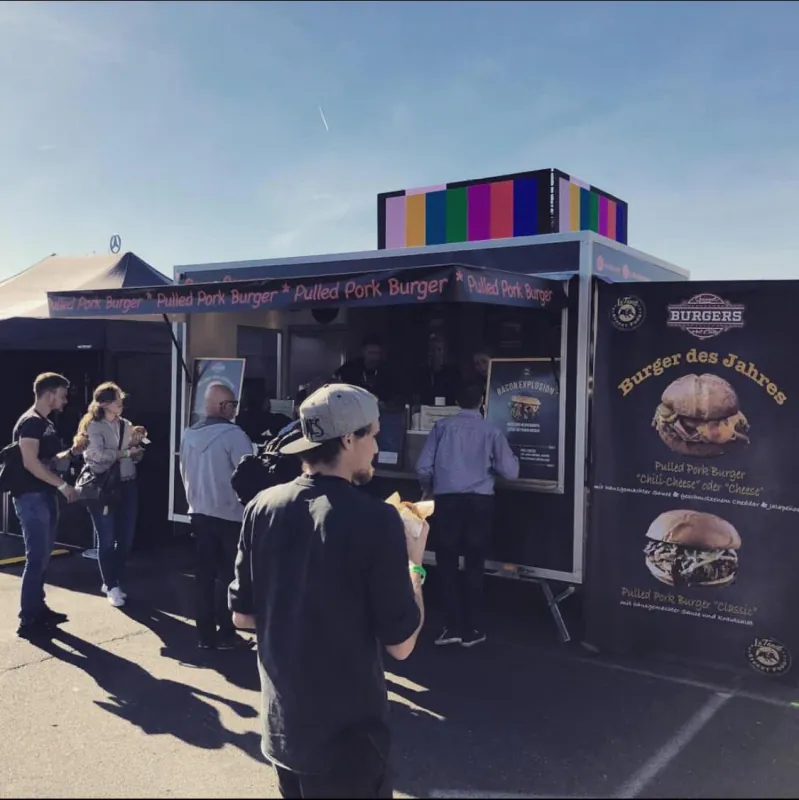 Gäste stehen am schwarzen La Tapita Foodtruck bei einem Event an